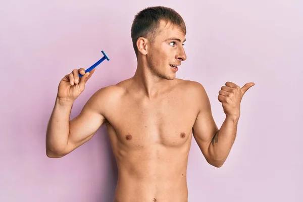 Young Caucasian Man Shirtless Holding Razor Pointing Thumb Side Smiling — Zdjęcie stockowe