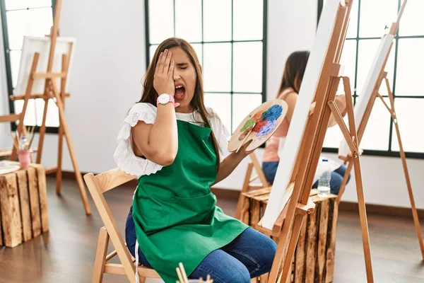 Młode Hiszpanki Malują Płótnie Pracowni Sztuki Ziewając Zmęczona Półtwarzą Okiem — Zdjęcie stockowe