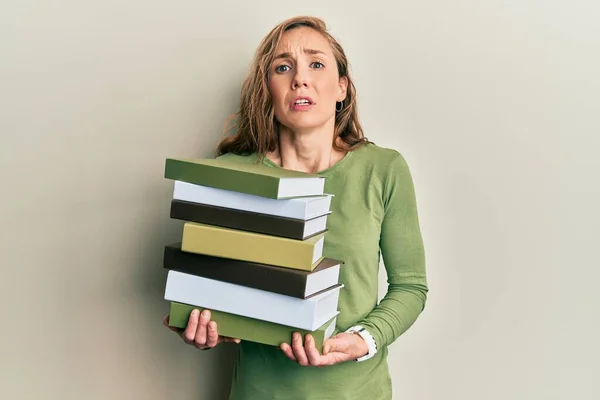 Young Blonde Woman Holding Pile Books Clueless Confused Expression Doubt — Foto de Stock