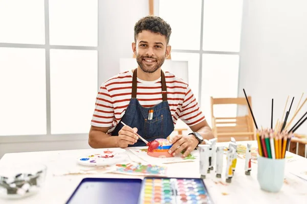 年轻的阿拉伯艺术家在艺术工作室高兴地微笑着绘画陶瓷 — 图库照片