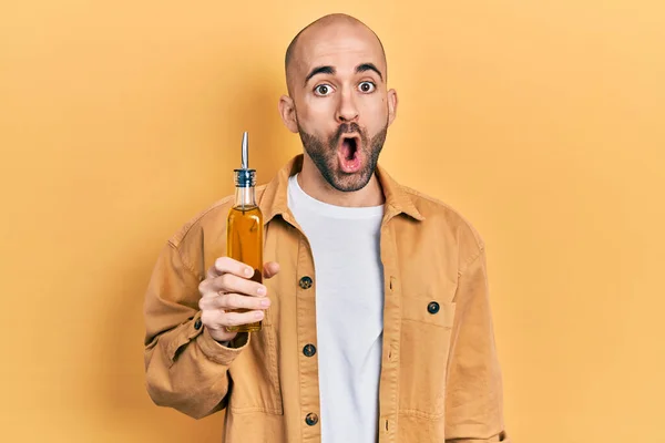 Young Bald Man Holding Olive Oil Can Scared Amazed Open — Stock Photo, Image