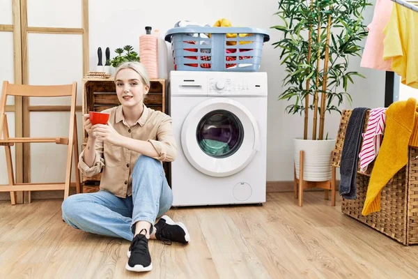 Ung Kaukasisk Kvinna Dricker Kaffe Väntan Tvättmaskin Tvättstugan — Stockfoto