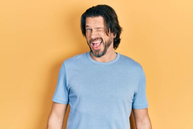 Orta yaşlı, günlük kıyafetler giyen, kameraya seksi bir ifadeyle bakan, neşeli ve mutlu yüzlü bir beyaz adam.. 