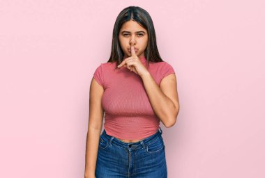 Gündelik tişört giyen genç İspanyol kız parmakları dudaklarında sessiz olmak istiyor. sessizlik ve gizli konsept. 