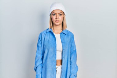 Yün şapka takan güzel sarışın kadın yüzünde ciddi bir ifadeyle rahatlamış. Basit ve doğal bir şekilde kameraya bakıyorsun.. 