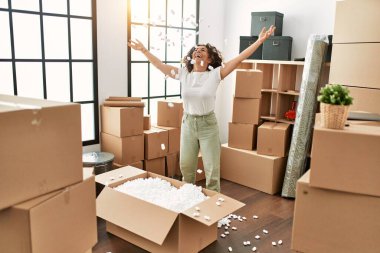 Orta yaşlı İspanyol kadın yeni evinde kutuları açarken gülümsüyor.