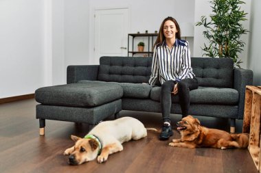 Kanepede oturmuş köpeklerle gülümseyen İspanyol bir kadın.