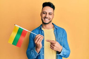 Young arab man holding lithuania flag smiling happy pointing with hand and finger 