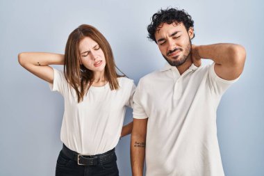 Young couple wearing casual clothes standing together suffering of neck ache injury, touching neck with hand, muscular pain 