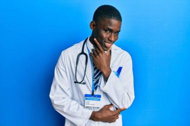 Young african american man wearing doctor uniform looking confident at the camera smiling with crossed arms and hand raised on chin. thinking positive. 