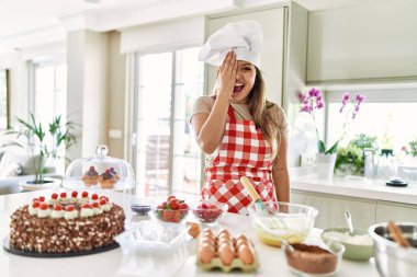 Güzel, genç, esmer pasta şefi kadın mutfakta hamur işi pişiriyor. Bir gözünü eliyle kapatıyor. Yüzünde kendine güvenen bir gülümseme ve sürpriz bir duygu var.. 