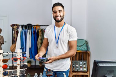 Genç Arap esnaf mağazasında kredi kartı ve veri telefonuyla ödeme yapıyor.