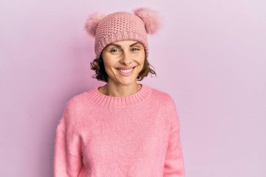 Genç esmer, sevimli yün şapkalı, yüzünde güzel bir gülümseme olan bir kadın. şanslı kişi. 