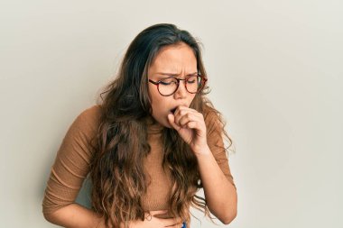 Günlük kıyafetler ve gözlük takan genç İspanyol kız kendini iyi hissetmiyor ve soğuk algınlığı veya bronşitin belirtisi olarak öksürüyor. sağlık hizmeti kavramı. 