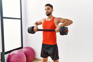 Young arab man training with dumbbells at sport center