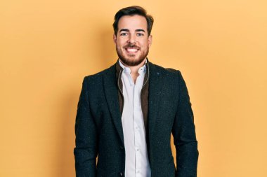 Handsome caucasian man with beard wearing elegant business jacket looking positive and happy standing and smiling with a confident smile showing teeth 