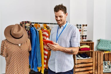 Elbise mağazasında çalışan dokunmatik ped kullanan, mutlu gülümseyen bir İspanyol esnaf..