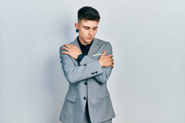 Young caucasian boy with ears dilation wearing business jacket hugging oneself happy and positive, smiling confident. self love and self care 