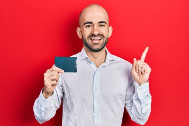 Young bald man holding ssd memory smiling happy pointing with hand and finger to the side 