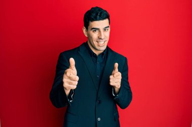 İş kıyafetleri giymiş yakışıklı İspanyol adam kamerayı mutlu ve komik suratıyla işaret ediyor. iyi enerji ve titreşimler. 