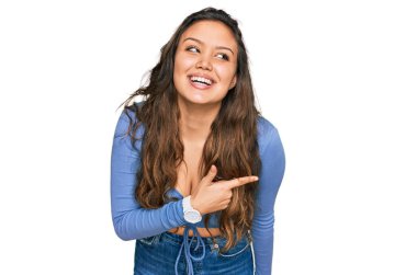 Gündelik kıyafetler giyen, neşeli, yüzünde bir gülümseme olan genç İspanyol kız mutlu ve doğal bir ifadeyle elini ve parmağını kaldırdı. 