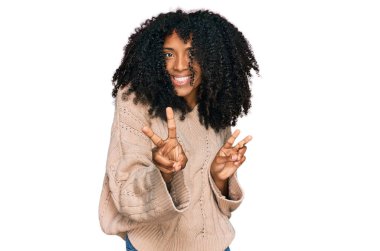 Gündelik giysiler giymiş, gülümseyen, parmaklarını zafer işareti yaparken gösteren genç Afrikalı Amerikalı kız. İki numara.. 
