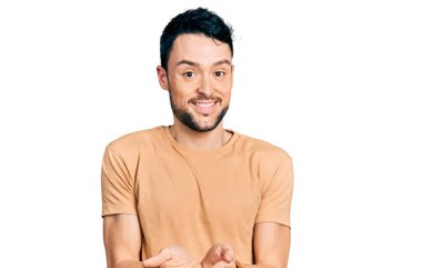 Sıradan tişörtler giyen, elleri avuçlarında gülümseyen ya da el hareketi yapan İspanyol bir adam. Bekleme ve koruma 