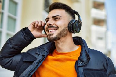 Yakışıklı, sakallı, neşeli ve kendine güvenen, kışlık palto giyen bir İspanyol.