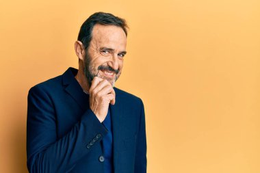 Middle age hispanic man wearing business clothes smiling looking confident at the camera with crossed arms and hand on chin. thinking positive. 