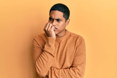 Kış süveteri giyen genç, yakışıklı, gergin ve ağzı tırnak ısıran bir İspanyol. anksiyete. 