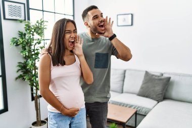 Bir bebek bekleyen ırklar arası genç bir çift hamile karnına dokunuyor bağırıyor ve ağızları açık bağırıyorlar. iletişim konsepti. 