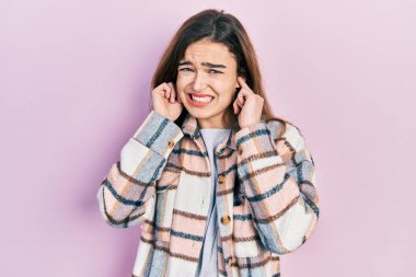 Gürültülü müzik sesi için kulaklarını parmaklarıyla kapatan günlük kıyafetler giyen beyaz bir genç kız. sağır kavramı. 