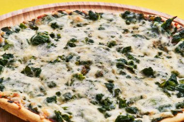  Sarı arka planda tek kişilik ıspanaklı İtalyan pizzası.