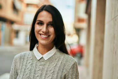 Genç İspanyol kadın gülümseyerek şehirde mutlu mesut dikiliyor..