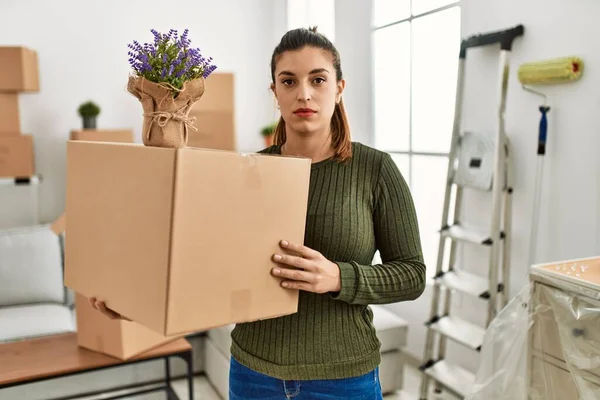 Young Hispanic Woman Holding Cardboard Box Moving Thinking Attitude Sober — ストック写真