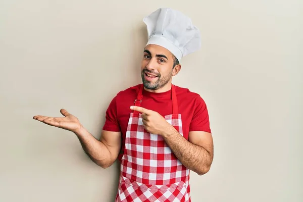 Young Hispanic Man Wearing Baker Uniform Amazed Smiling Camera While — Stock fotografie