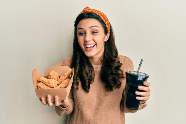 Young Hispanic Woman Eating Chicken Wings Drinking Soda Smiling Laughing — Stockfoto