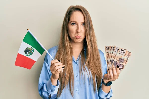 メキシコの国旗とメキシコのペソ紙幣を持っている若いブロンドの女性は 怒りと恐怖を叫び 苦痛のために落ち込んで心配しています 悲しい表情 — ストック写真