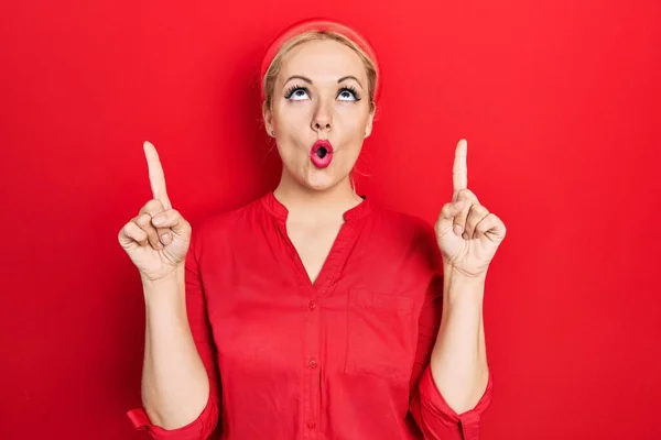 Young Blonde Woman Wearing Casual Red Shirt Amazed Surprised Looking — Fotografia de Stock
