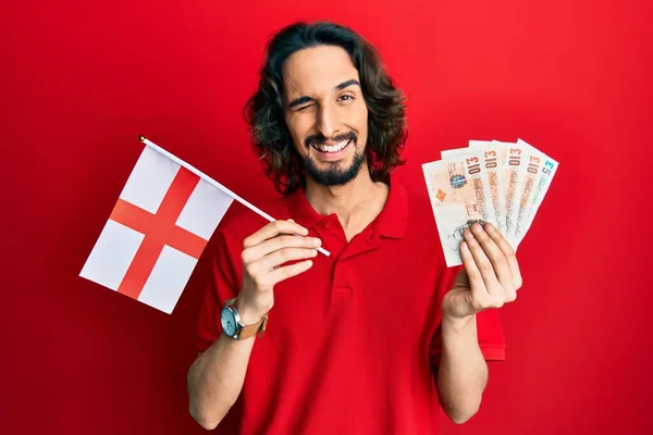 Young Hispanic Man Holding England Flag Pounds Banknotes Winking Looking —  Fotos de Stock