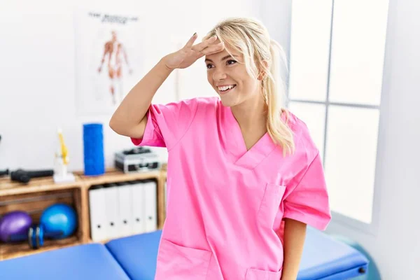 在疼痛康复诊所工作的年轻的高加索女人非常快乐 面带微笑地看着远方 手牵着手 搜索概念 — 图库照片