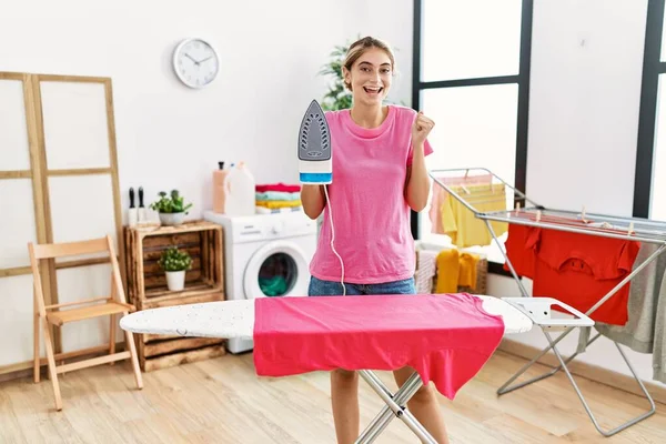 Young Blonde Woman Ironing Clothes Home Screaming Proud Celebrating Victory —  Fotos de Stock