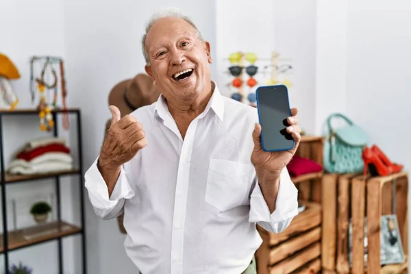 Senior Man Holding Smartphone Retail Shop Pointing Thumb Side Smiling — Stockfoto