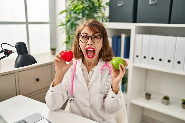 Young Doctor Woman Holding Heart Green Apple Angry Mad Screaming — ストック写真