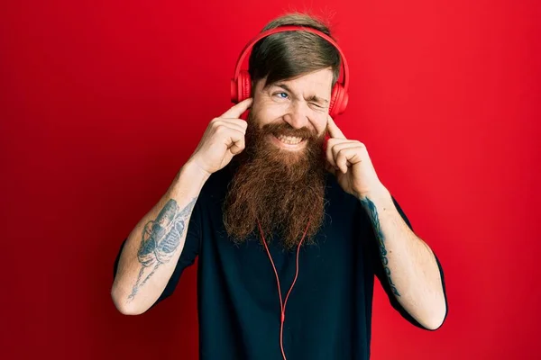 Redhead Man Long Beard Listening Music Using Headphones Covering Ears — Stock Photo, Image