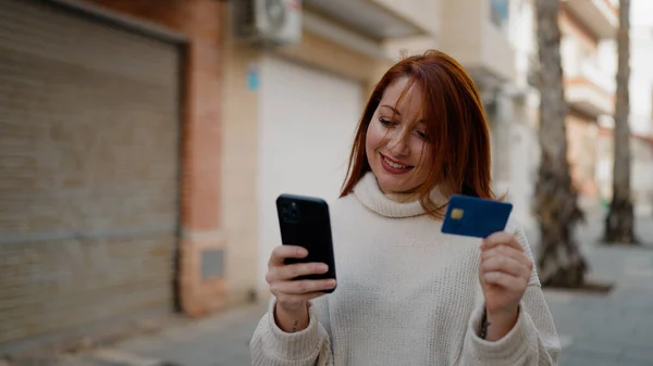 ストリートでスマートフォンやクレジットカードを使っている若い赤毛の女性 — ストック写真