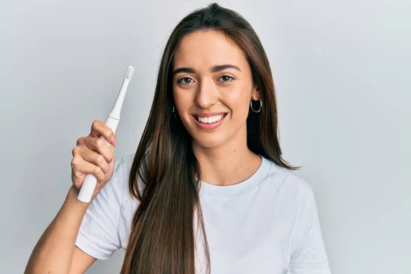 Joven Chica Hispana Sosteniendo Cepillo Dientes Eléctrico Con Aspecto Positivo —  Fotos de Stock