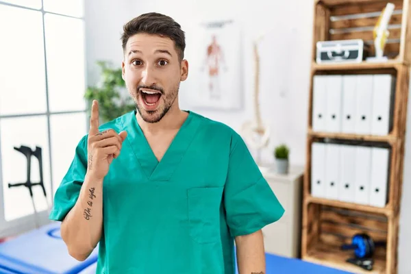 Young Physiotherapist Man Working Pain Recovery Clinic Pointing Finger Successful — Stockfoto