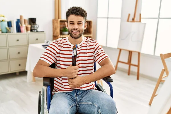 Joven Artista Árabe Discapacitado Sosteniendo Pinceles Sentado Silla Ruedas Estudio — Foto de Stock