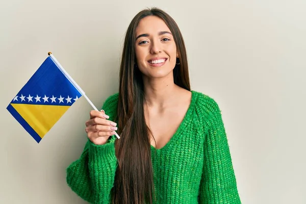 Young Hispanic Girl Holding Bosnia Herzegovina Flag Looking Positive Happy — Stockfoto